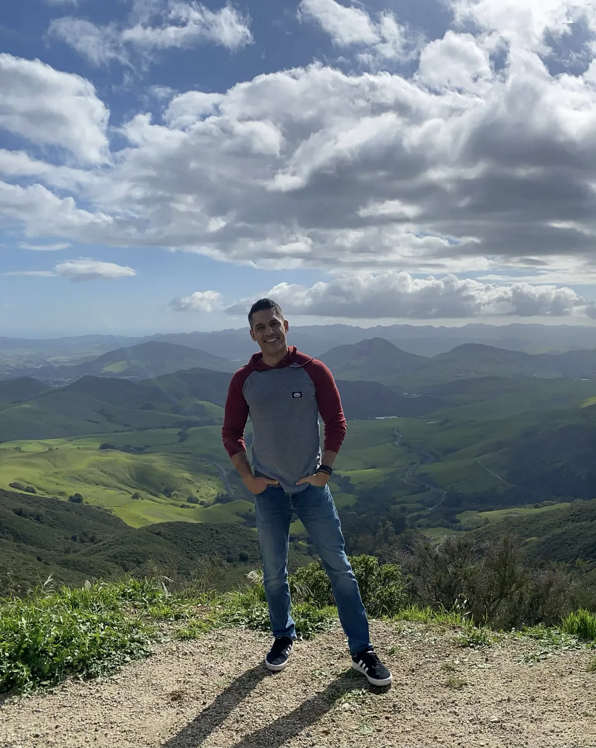 Wes Lemos standing on a mountain overlook beneath dramatic clouds